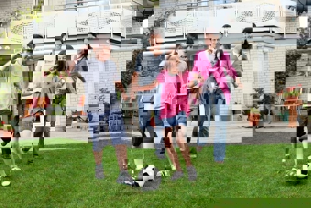 A family plays soccer in their backyard