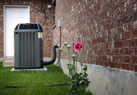 A gray heat pump sits on green grass