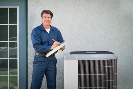 HVAC technician with clipboard stands next to an AC unit