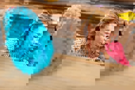 A woman holds her nose and uses a feather duster to clean