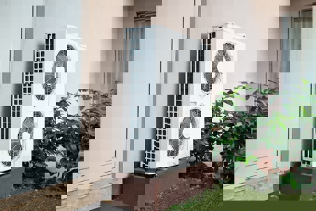 A white heat pump sits outside a home