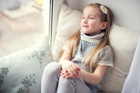 A girl in a sweater sits in a window seat