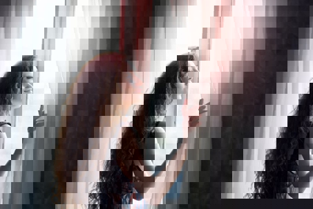 Woman opens curtains to a sunlit room