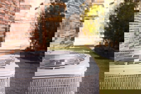 An AC unit sits on a lawn