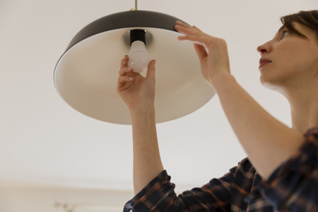 A woman replaces a lightbulb