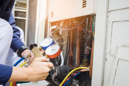 An HVAC technician repairs an outside unit