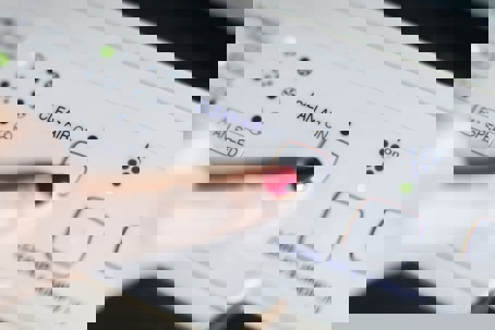 A finger pressing the "Clean Air On" button on a white air purifier