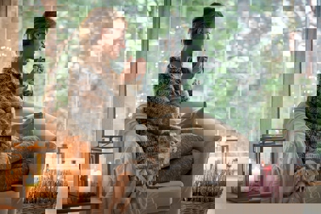 A woman sits on her sofa enjoying a cup of coffee