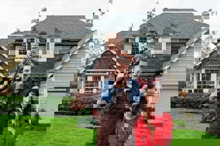 A happy family stands in front of their well-maintained home