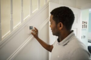 Man Pressing HVAC Thermostat